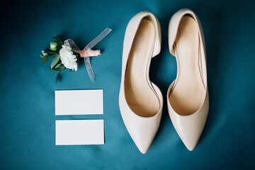 wedding shoes with boutonnieres and cards on blue background