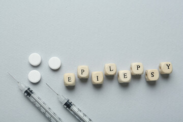 Word Epilepsy, syringes and pills on light grey background, flat lay. Space for text