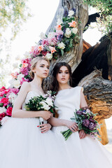 two brides with bouquets on a background of flowers