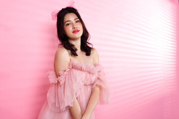 Portrait of Asian girl wear pink dress over pink tone background