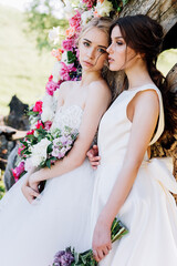 two brides with bouquets on a background of flowers