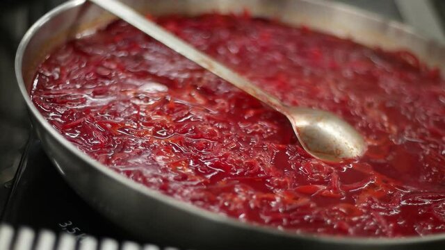 Close-up shot of cooking tomato sauce in a steel frying pan. Media. Boiling and seething while preparing a beautiful red dish