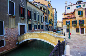 Fototapeta na wymiar Small romantic water canal with stone bridge in Castello region in Venice, Italy