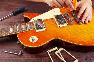 Guitar technician tune the height bridge on electric guitar at workplace.