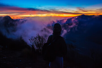 Silhouette of the girl looking at Bromo volcano on sunrise. Mount Bromo is an active volcano in Tengger Semeru National Park, East Java, Indonesia
