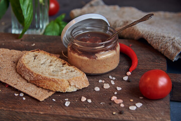 Handmade chicken pate in a glass jar on a wooden board .