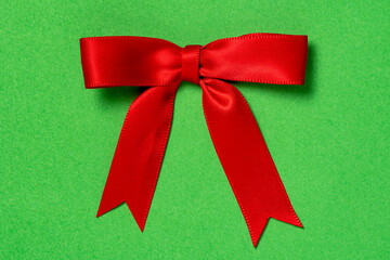 Red ribbon satin gift bow on the green background