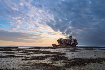 An old abandoned ship on the shore of the drying up Aral Sea. Kazakhstan. Abandoned ships sawn for scrap by local residents. Ecological disaster of the Aral Sea