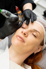 Cosmetologist doing permanent makeup eyebrows. Care and beauty concept