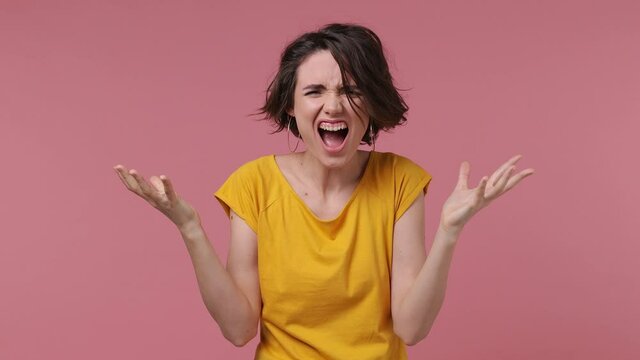 Displeased crazy irritated sad angry mad brunette short hairdo young woman 20s wears basic casual yellow t-shirt isolated on pastel pink background studio portrait People emotions lifestyle concept