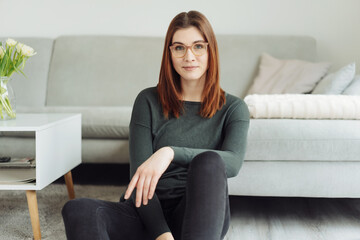 Thoughtful quiet young woman wearing glasses relaxing at home