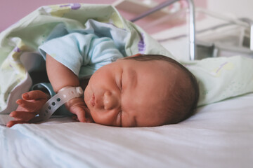 Newborn baby peacefully sleeping in hospital room after delivery. First days life of baby after...