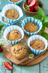 Healthy homemade cakes, summer dessert. Gluten free strawberry oatmeal muffins and fresh strawberries on a rustic wooden table.