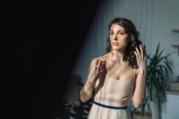 Obraz premium Close up studio portrait of a pretty brunettes looking at the sun. Part of the frame covered the interior detail