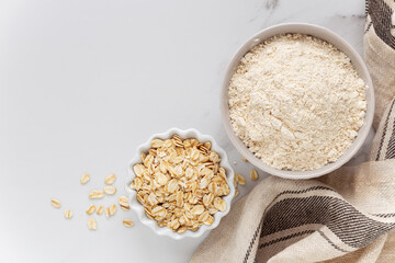 Oat flour and oats on white marble background. Concept of gluten free cooking and baking