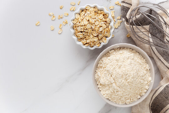 Oat flour and oats on white marble background. Concept of gluten free cooking and baking