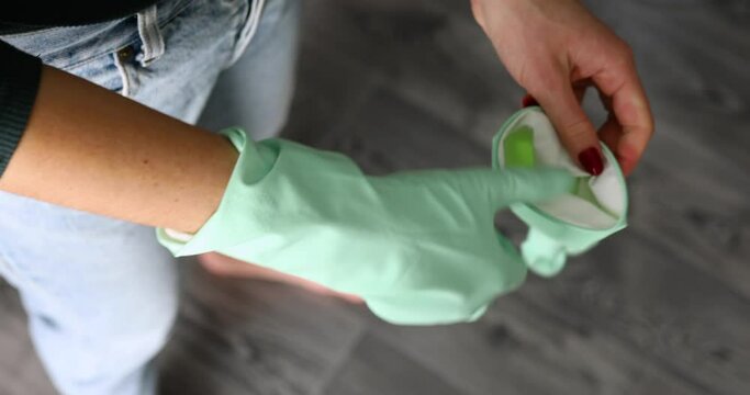 Unrecognizable female putting on latex gloves while preparing to clean house, wash dish at home. Woman wife do daily house cleaning routine.