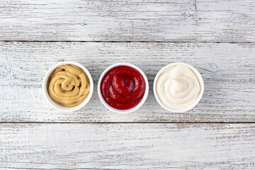 Set of three kinds of classic sauces on wooden background. Mayonnaise ketchup mustard