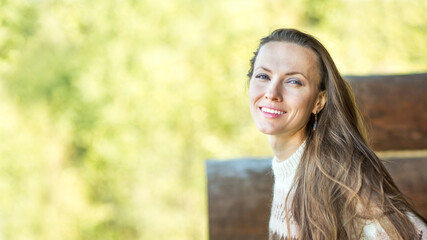 Positive nice young woman smiling while standing on a wooden terrace and breathing fresh air