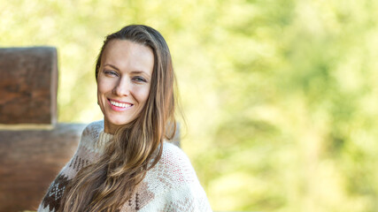 Positive nice young woman smiling while standing on a wooden terrace and breathing fresh air