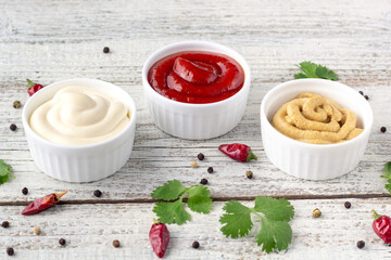 Set of various sauces with spices on white wooden background. Mayonnaise ketchup mustard.