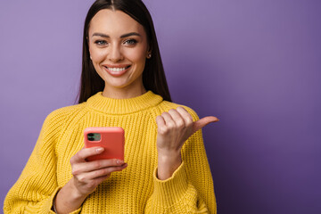 Happy young woman wearing sweater holding mobile phone