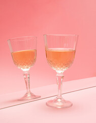 glass of wine in reflection in the mirror on pink pastel background. summer abstract creative idea. minimal background