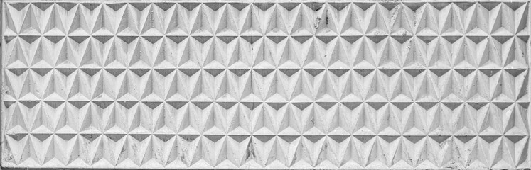 Texture of a wide decorative concrete wall panel with geometric pattern in the form of embossed triangles.