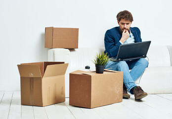 Manager sits on the couch with a laptop working professional boxes with things