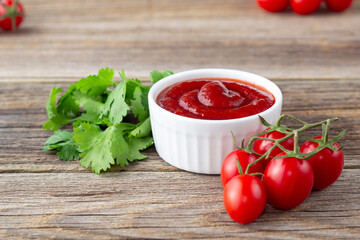 White bowl of tomato sauce with parsley and tomato. Ketchup on natural wooden background