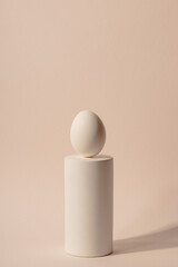 One white Easter egg on podium against a neutral background. Minimalism and simplicity aesthetics. High quality photo