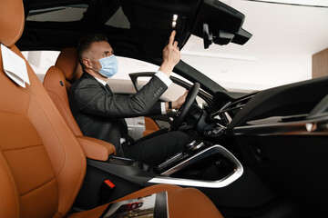 Mature white man choosing and examining car in showroom