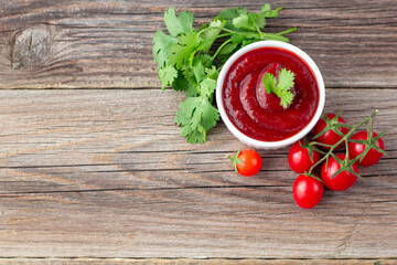 White bowl of tomato sauce with parsley and tomato. Ketchup on natural wooden background