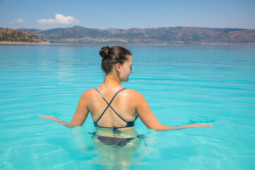 Obraz premium A young sexy female in swim suit is swimming in turquoise crater lake Salda Golu, Turkey