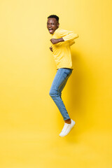 Fototapeta na wymiar Young cheerful excited African man jumping with clenching hands on isolated yellow studio background