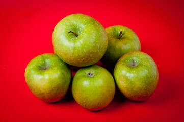 Large green apples, ripe and juicy. Photographed against a uniform red background.