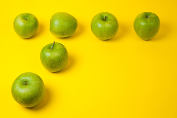 Large green apples, ripe and juicy. Photographed against a uniform yellow background.