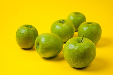 Large green apples, ripe and juicy. Photographed against a uniform yellow background.