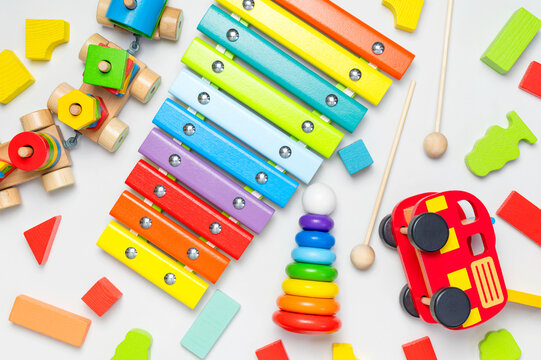 Children's toys made of natural wood on white background. Multi-colored pyramid, train, constructor, xylophone in rainbow colors. Eco friendly toy, plastic free. Toy for babies and toddlers Flat lay