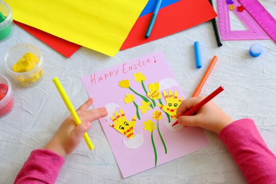 Child making card with Easter funny eggs and flowers  from colorful paper. Handmade. Project of children's creativity, handicrafts, crafts for kids. Happy easter inscription