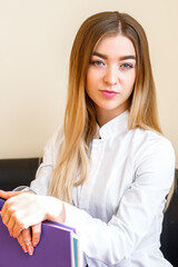Portrait of beautiful young caucasian businesswoman with folders standing and looking at the camera in the office