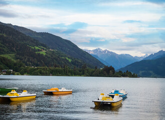Fototapeta na wymiar Colorful pedal boats overlooking the alps mountains in the town of zell am see in austria on a camping.