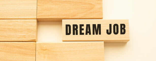 DREAM JOB text on a strip of wood lying on a white table.