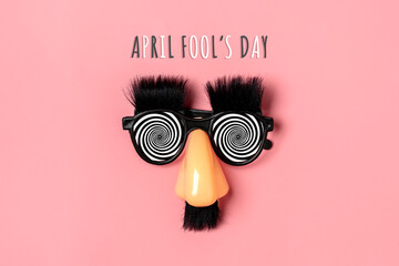 funny face - fake eyeglasses, nose and mustache, confetti, sequins on pink background Happy fools...