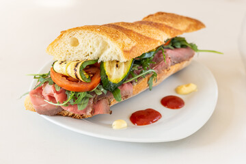 Bar sandwich with roast beef, grilled zucchini, tomato, rocket, ketchup
