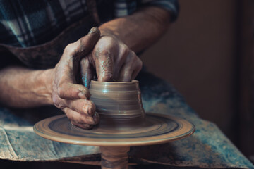 In the ceramics workshop. Beautiful hands of the master make peas on a potting wheel. Place for your text.