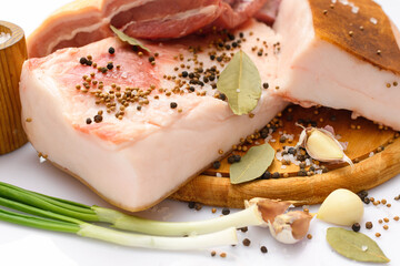 raw pork meat and lard with salt, spices and garlic on a cutting board, white background