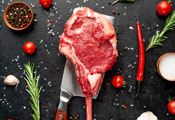 raw tomahawk beef steak on the knife with spices on stone background