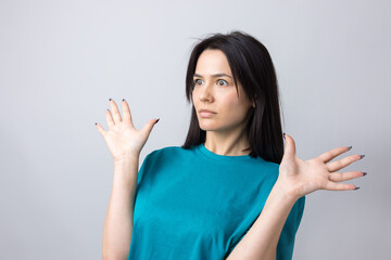 Young beautiful woman with facial expression of surprise standing over gray background.