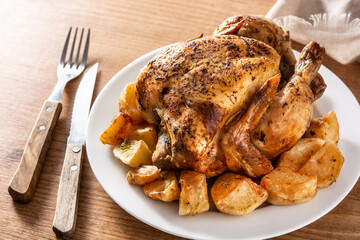 Homemade roasted chicken with potatoes on wooden table